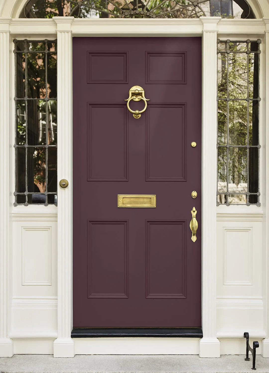 A classic six-panel front door in deep burgundy with polished gold hardware, including a knocker, letterbox, and handle, set within a white paneled entryway frame.